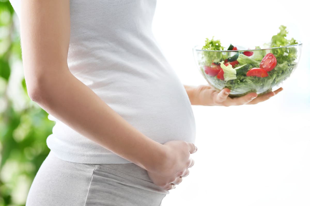 Pregnant woman holding a fresh salad bowl for prenatal nutrition